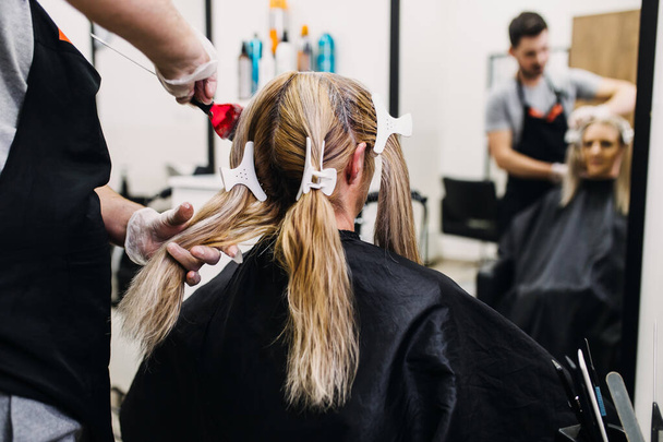 Peluquería es el pelo femenino moribundo, haciendo que el cabello resalte a su cliente con una lámina.  - Foto, Imagen