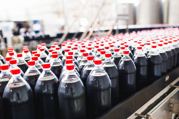 瓶詰め工場-ボトルにジュースを処理し、瓶詰めするための黒ジュース瓶詰めライン。選択的焦点.  - 写真・画像