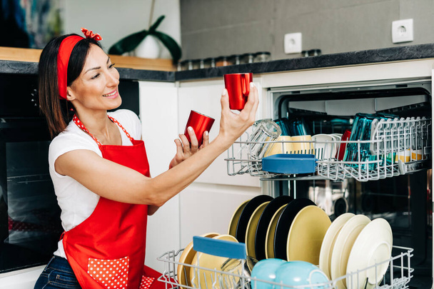 Mulher bonita tirando pratos limpos da máquina de lavar louça - Foto, Imagem