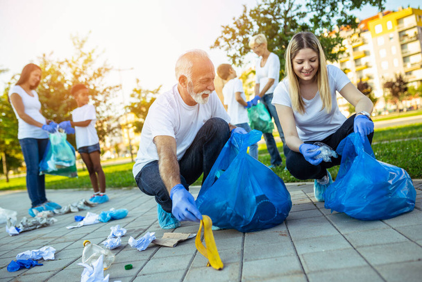 Vapaaehtoiset roskapussien kanssa siivoamassa roskia ulkona - ekologia - Valokuva, kuva