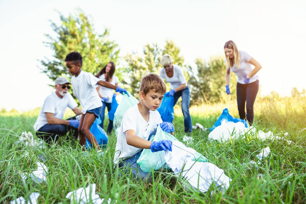 Voluntarios con bolsas de basura limpiando basura al aire libre - concepto de ecología. - Foto, imagen