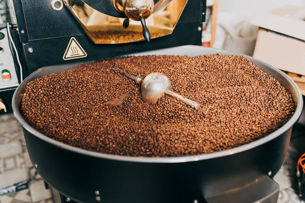 Granos de café aromáticos recién tostados sobre una moderna máquina de tostado de café. - Foto, imagen