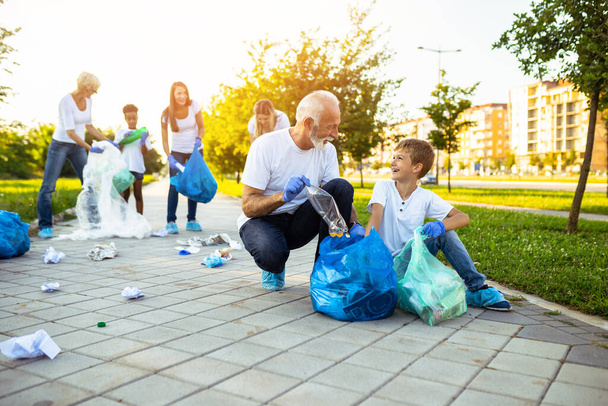 Voluntarios con bolsas de basura limpiando basura al aire libre - concepto de ecología. - Foto, Imagen