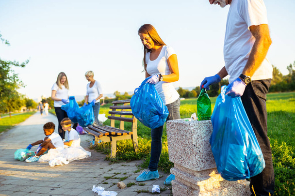 Εθελοντές με σακούλες σκουπιδιών καθαρίζουν τα σκουπίδια σε εξωτερικούς χώρους - ecology concept. - Φωτογραφία, εικόνα