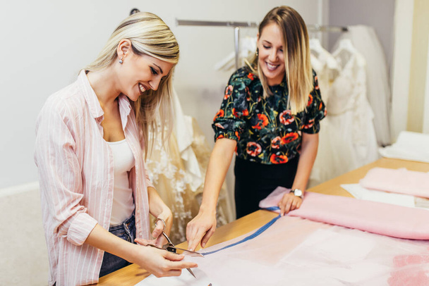 Дизайнери моди працюють в салоні для шиття весільних суконь
. - Фото, зображення