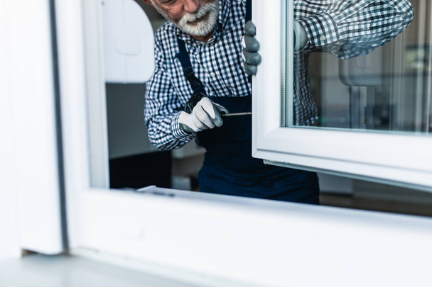 Senior klusjesman repareert raam. Renovatie. - Foto, afbeelding