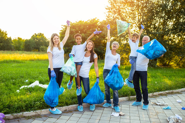 ゴミ袋を持つボランティアが屋外でゴミをきれいにする-生態学の概念. - 写真・画像