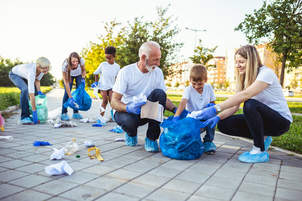 Волонтери зі сміттєвими мішками прибирають сміття на відкритому повітрі концепція екології
. - Фото, зображення