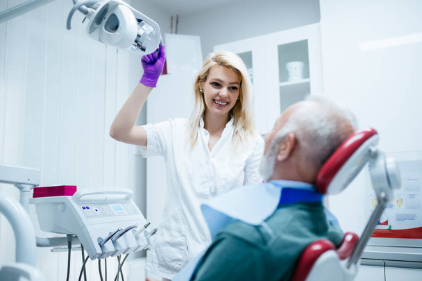 muotokuva hymyilevästä hammaslääkäristä potilaan kanssa hammashoitolassa - Valokuva, kuva