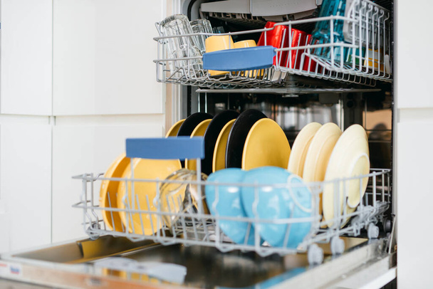 Сучасна відкрита посудомийна машина з чистим посудом на білій кухні
. - Фото, зображення