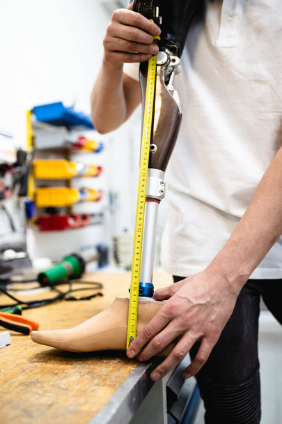 Hombre discapacitado que trabaja en una tienda de amputados para la producción de piezas de prótesis para extremidades. - Foto, imagen