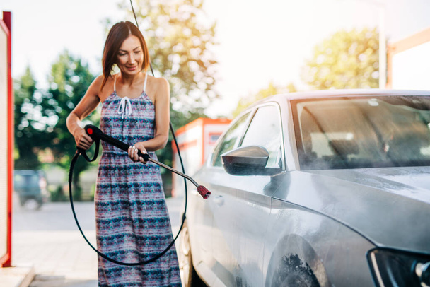 Happy středního věku žena mytí auta v myčce aut pomocí vysokotlaké vodní automat. - Fotografie, Obrázek
