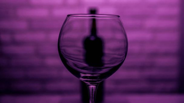  Wine glass empty with a bottle on a brick wall background on a pink background - Photo, image