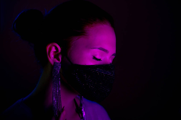 Young beautiful fashionable woman in protective mask with rhinestones dancing in bar or club. - Φωτογραφία, εικόνα