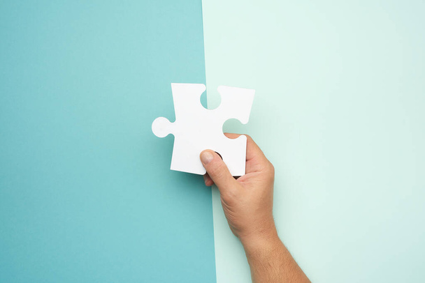 man hand houden groot papier wit blanco puzzels op een blauwe achtergrond, concept van het bedrijfsleven - Foto, afbeelding