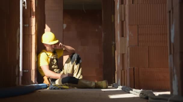Kaukaski wykonawca budowy w jego 40 Noszenie twardej czapki i okularów bezpieczeństwa odpoczynku podczas przerwy obiadowej - Materiał filmowy, wideo