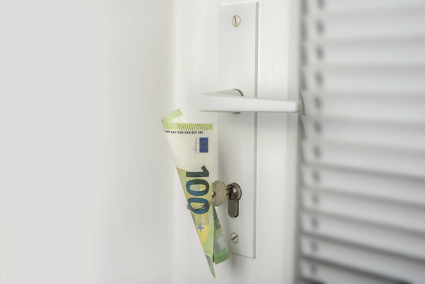 Money in a door key ring. Save money on your own house or apartment concept - Photo, Image