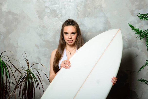 Beautiful young woman posing with surfboard in studio - Photo, Image