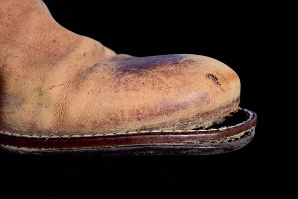 Крупный план старой кожаной туфли с наклонной подошвой, на темном фоне - Фото, изображение