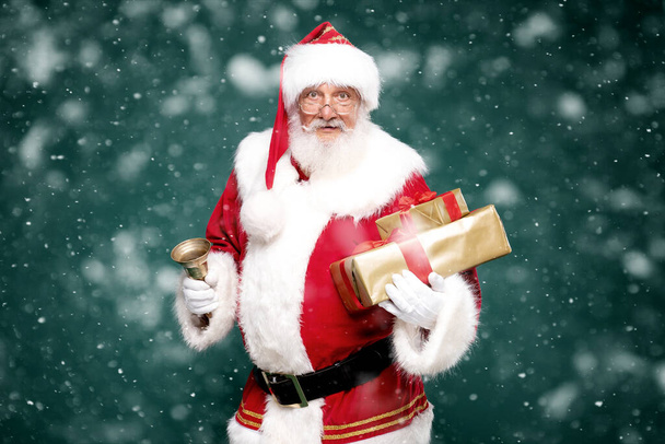 Portrait of the real, good old Santa Claus holding gift boxes. Green studio background. - Zdjęcie, obraz