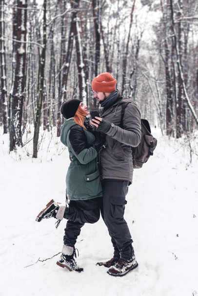 Portreyi kapat. Çift kış tatilinde arka planda karlı orman olan akıllı bir telefonda video izliyor. akıllı telefon kullan, boşluğu kopyala. - Fotoğraf, Görsel