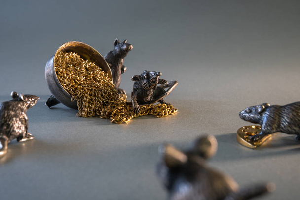 Összetétel fém patkány aranyból és ezüstből. A patkányok osztoznak a prédán. Harcolj az aranyért. Egy rakás arany lánc. A 2020-as év koncepciója a keleti naptárban. A gazdagság szimbóluma. Szürke háttér - Fotó, kép