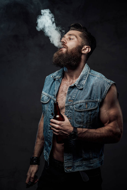 Fashionable naked guy with beard posing smoking vape - Фото, изображение