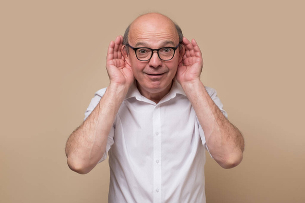 Hombre calvo mayor adulto en gafas escuchando atentamente, espiando, siendo curioso - Foto, Imagen