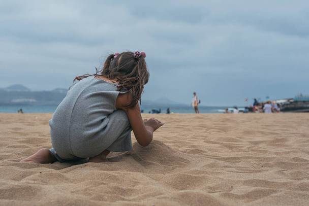 A Caucasian little girl playing with sand in the beach - Fotó, kép