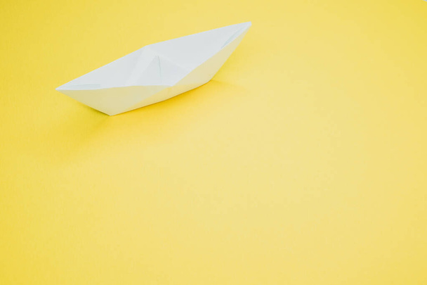 Eine Draufsicht auf ein weißes Papierboot isoliert auf gelbem Hintergrund - Foto, Bild
