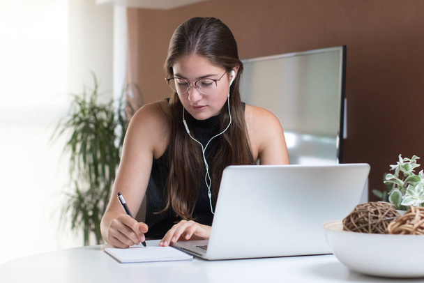 portrait of young woman wearing earphones and working with a laptop at home - Φωτογραφία, εικόνα