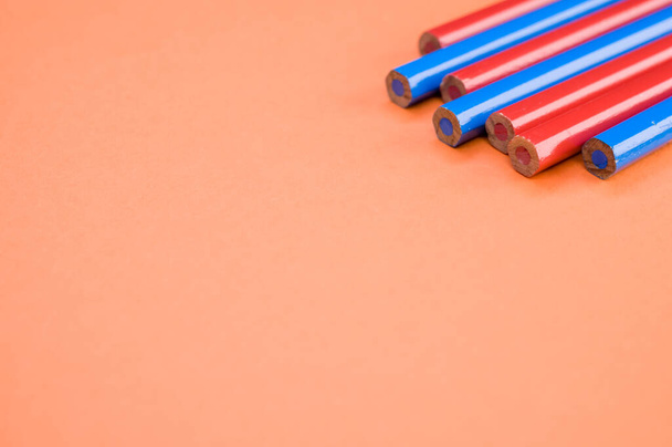 Un plano de alto ángulo de lápices rojos y azules sobre una superficie roja - Foto, Imagen