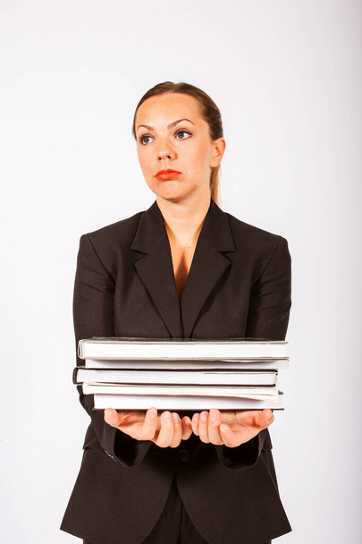 blond woman in a suit holding a stack of books and looking stressed - Photo, Image