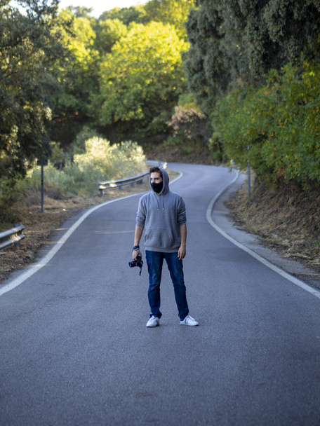 顔のマスクを持つ道路を歩いて若いヨーロッパの男性-コヴィト-19の後の新しい通常 - 写真・画像