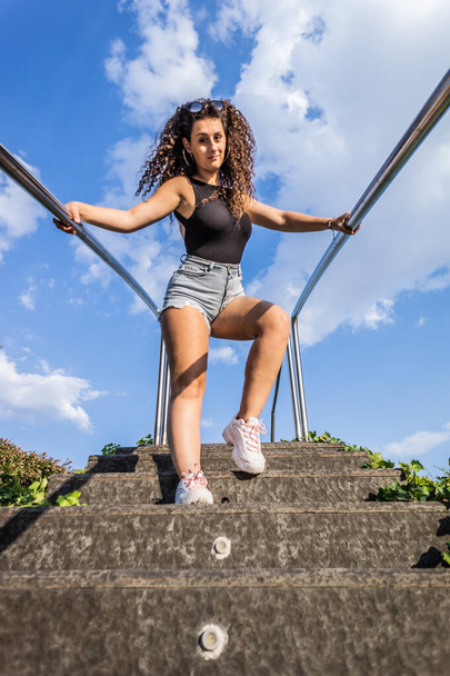 A low angle vertical shot of an attractive female holding a stairway railing - Fotó, kép