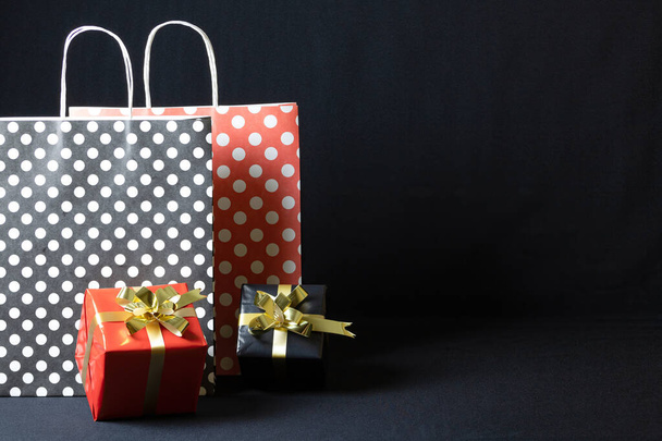 A polka dots paper bags with Christmas gift boxes isolated on a dark background - 写真・画像