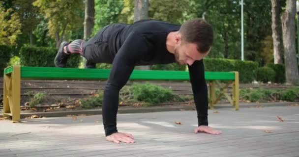 Deportista haciendo pies elevados flexiones en el banco del parque - Imágenes, Vídeo