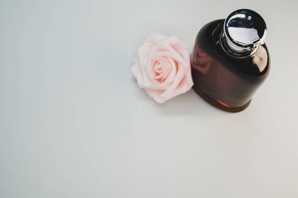 A rose perfume bottle and a rose on a gray background - 写真・画像