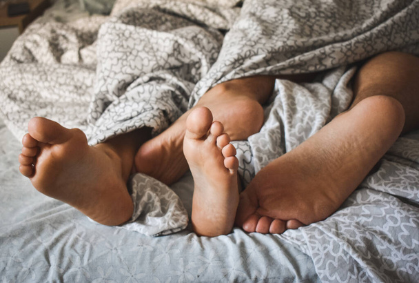 The feet of a loving couple sleeping in the bed - Фото, изображение