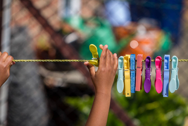 Un jeune enfant noir jouant avec des chevilles de vêtements et une corde à laver dans le jardin - Photo, image