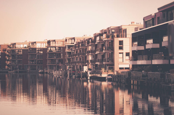 A Row of modern buildings near a reflective lake in Emden, Germany - 写真・画像