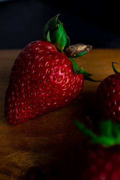 A closeup shot of a fresh juicy strawberry on a wooden board - Foto, immagini