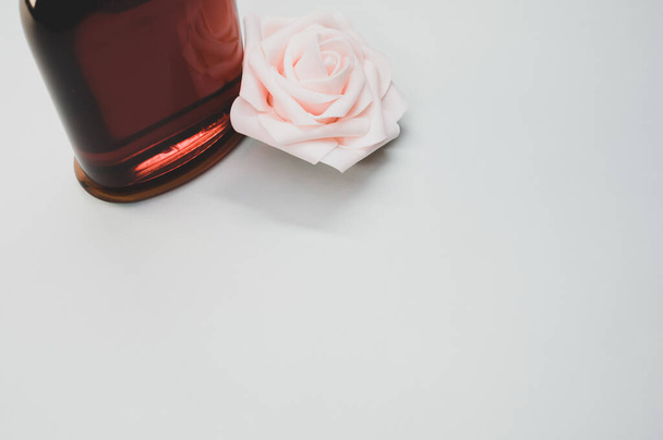 A rose perfume bottle and a rose on a gray background - Photo, image