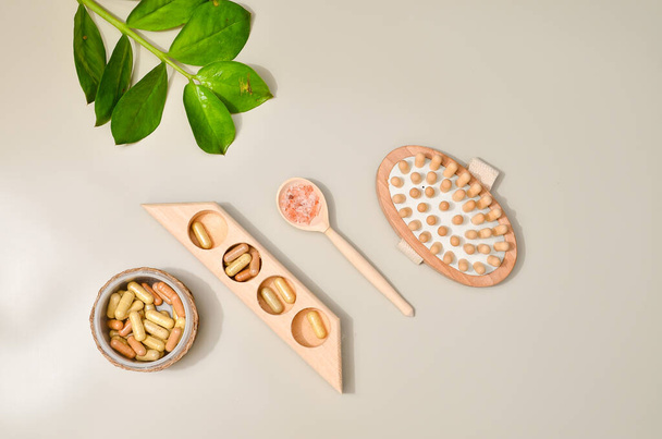 Spa beauty products for body and face home skin care, view from above on various spa treatment stuff, blank space for a text. Pills with herb in capsules in wooden bowl, pink sea salt - Foto, imagen