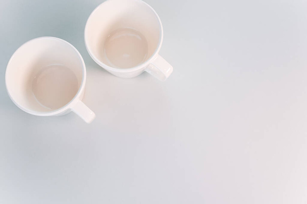 A top view of two white coffee cups on a white surface - 写真・画像