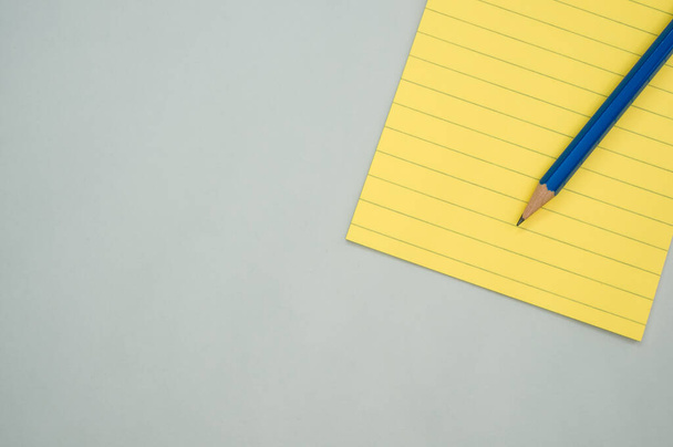 A top view of a notepad with a pencil isolated on a gray background - Photo, image