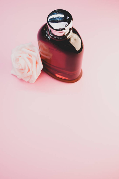 A rose perfume bottle and a rose on a pink background - Foto, Imagen