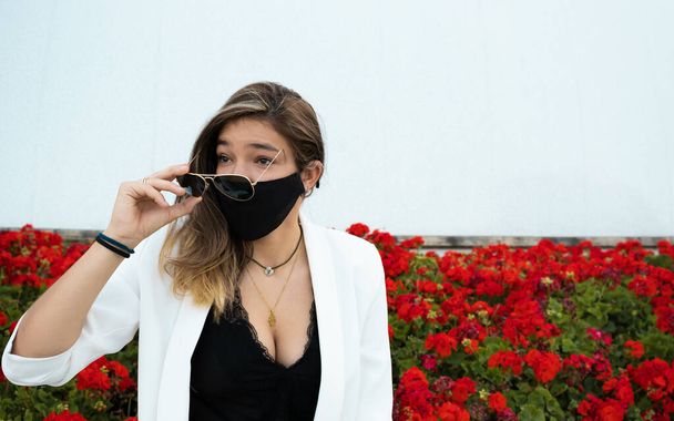 A closeup shot of a stylish girl with sunglasses wearing a sanitary mask - the new normal - Foto, Bild