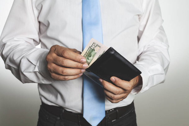 A businessman holding a leather wallet with money - Foto, afbeelding