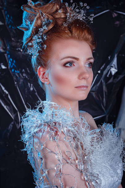 Snow Queen High Fashion Portrait over Blue ice Background (en inglés). retrato creativo de primer plano. Mujer joven en imagen creativa con maquillaje artístico plateado. Retrato de invierno. - Foto, Imagen